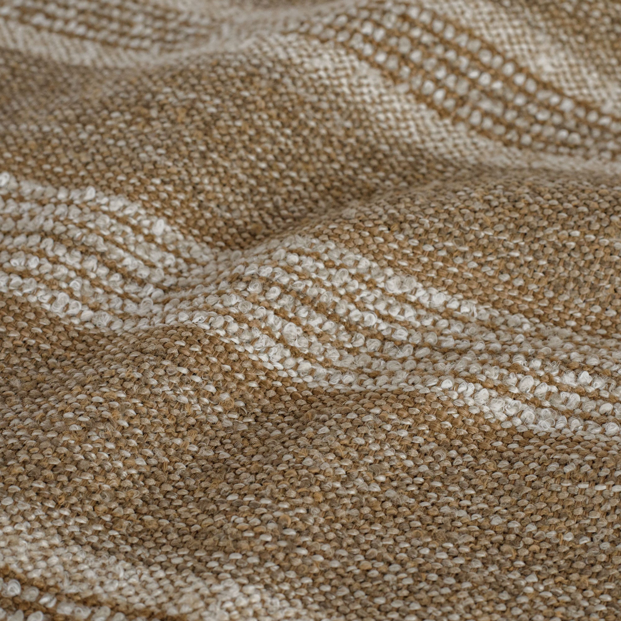 A cozy brown and beige upholstery fabric from Tonic Living with a basketweave and bouclé texture: close-up view.