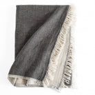 Alba Throw Blanket Charcoal, a reversible charcoal gray and natural linen cotton throw blanket with a delicate fringe edge from Tonic Living