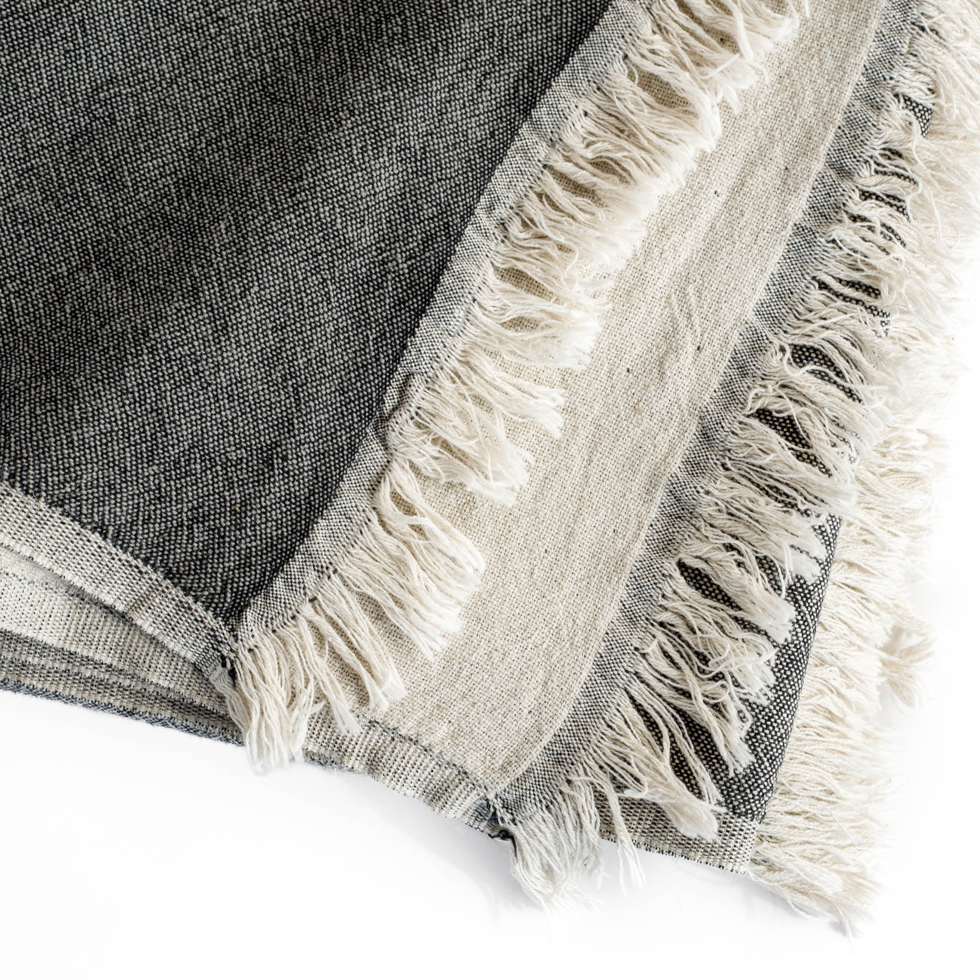 a charcoal grey and natural linen cotton throw blanket with a delicate fringe edge : close up view