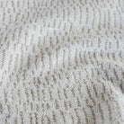 Avani Sand, a soft white fabric with a subtle pattern of beige thatched lines: close up view.