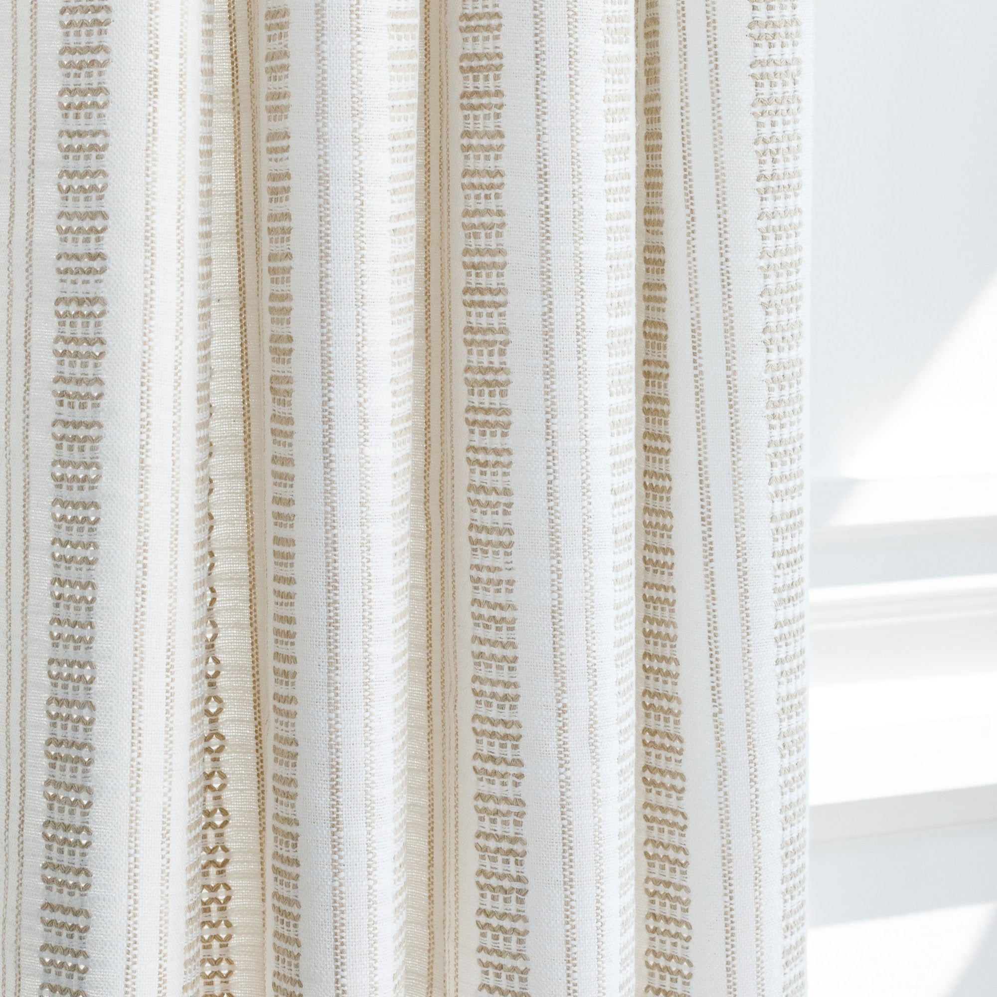 a white and tan intricate woven striped curtain fabric with a european flair