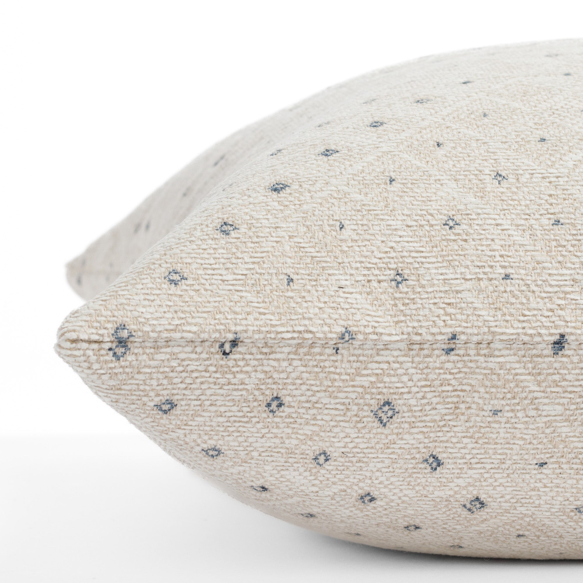 A neutral diamond patterned toss pillow: close up side view.