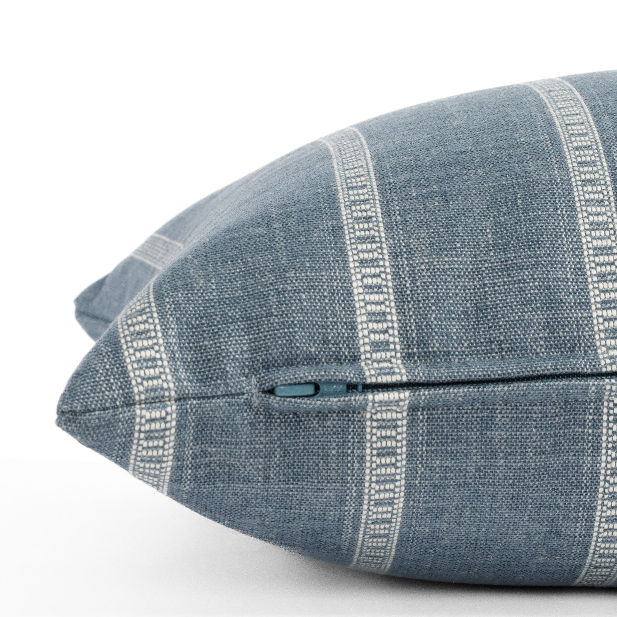 A blue and white striped lumbar pillow: close up zipper view.