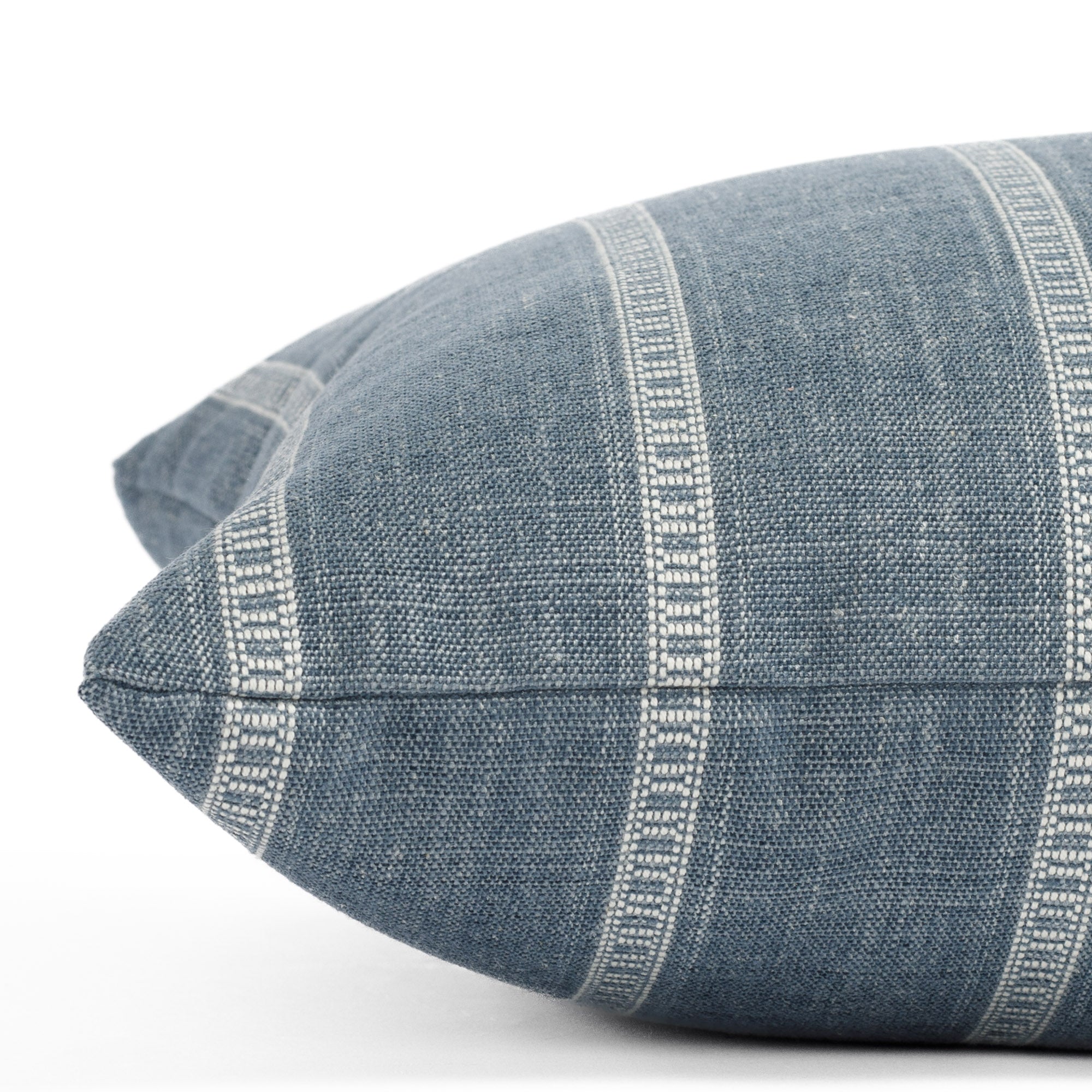 A blue and white striped bolster pillow: close up side view.