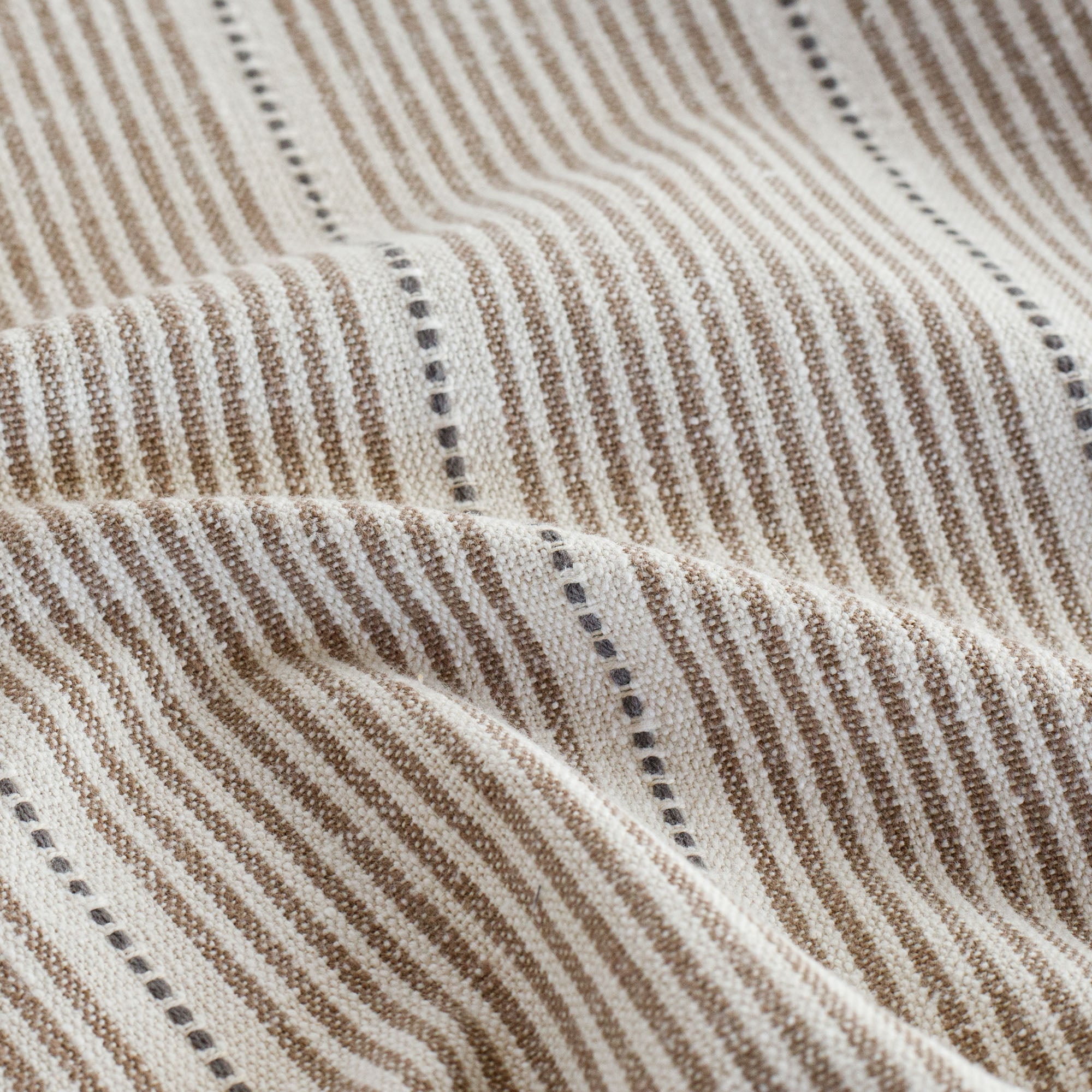 a brown, cream and black stripe patterned home decor fabric : close up view