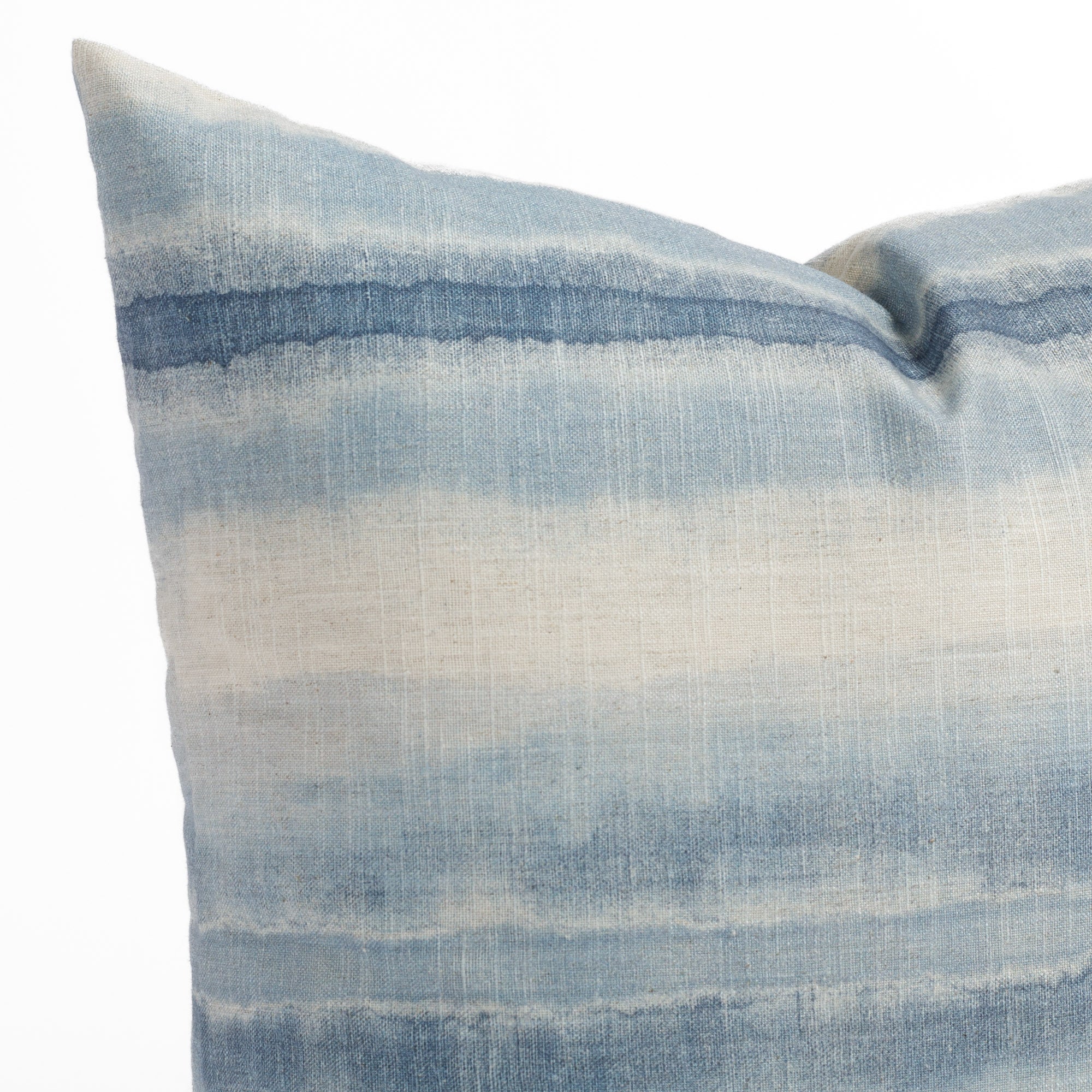 A chambray blue and sand throw pillow with ombre stripes: close up view.