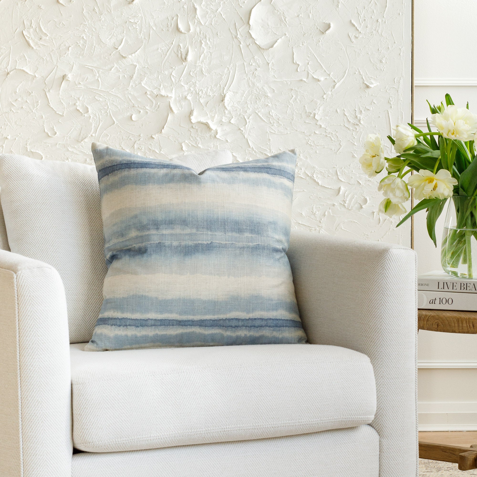 A blue and white pillow, styled on furniture.