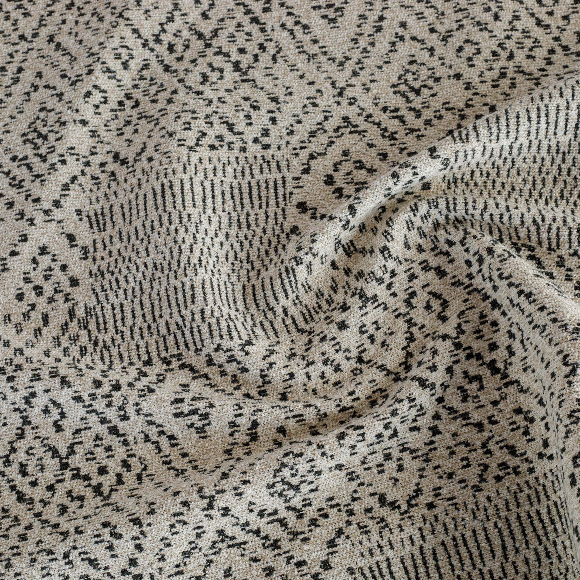 A black and tan Tonic Living upholstery fabric featuring a pattern of softly worn dots and lines.