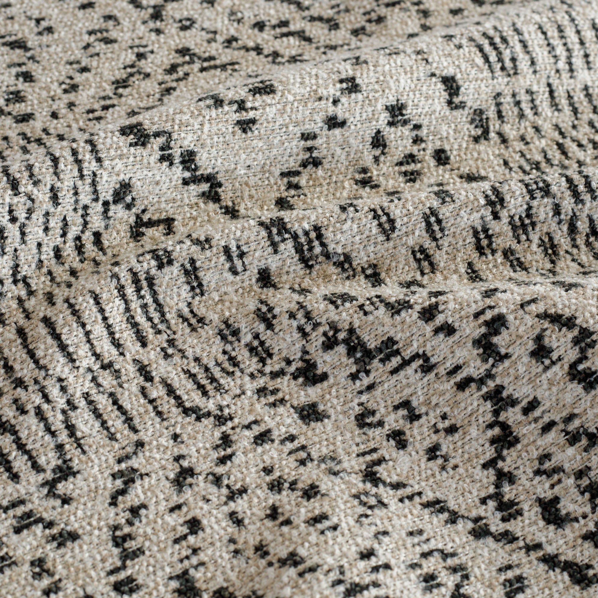 A textural beige and black patterned upholstery fabric: close up view.