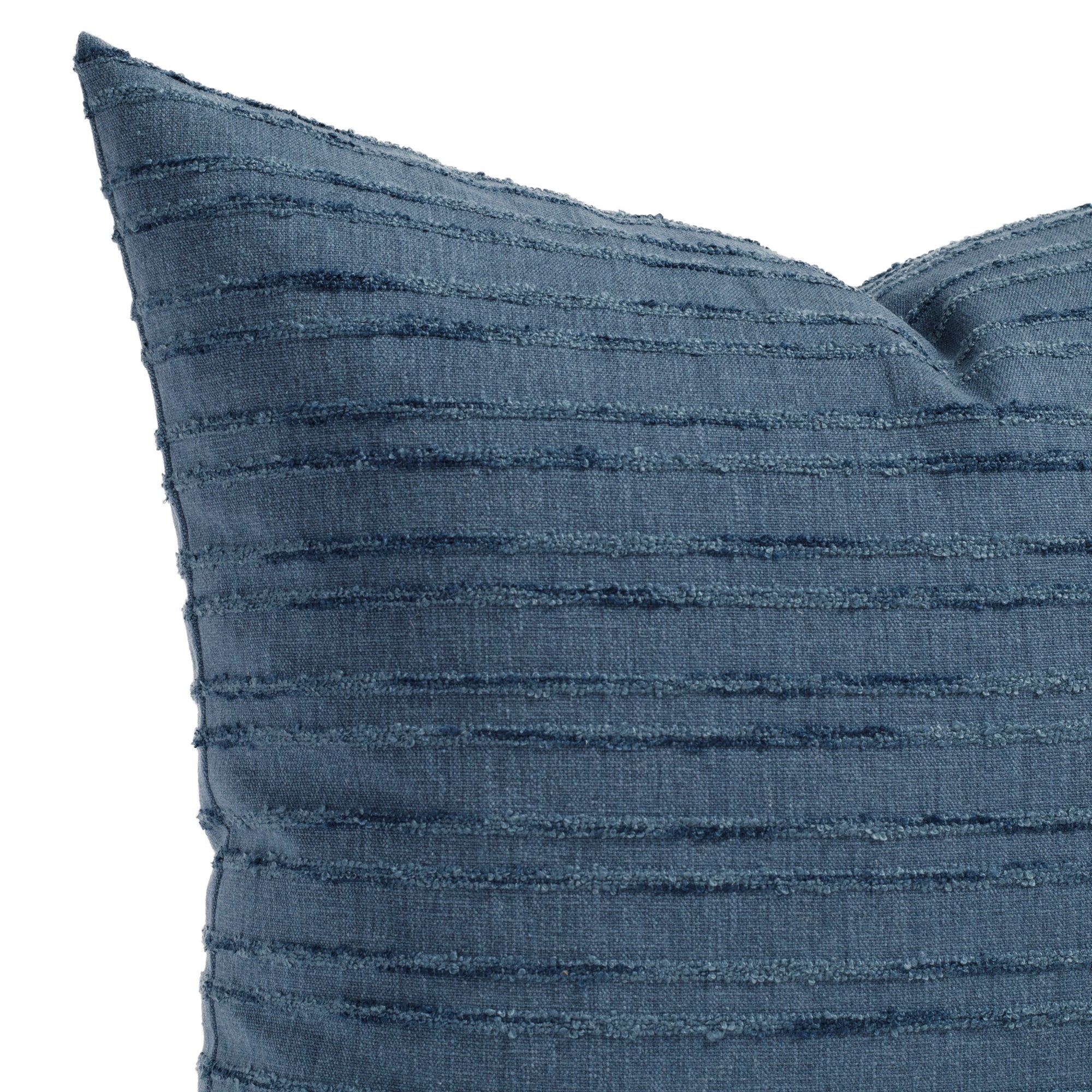 A faded navy blue pillow with textured tonal stripes: close up view.