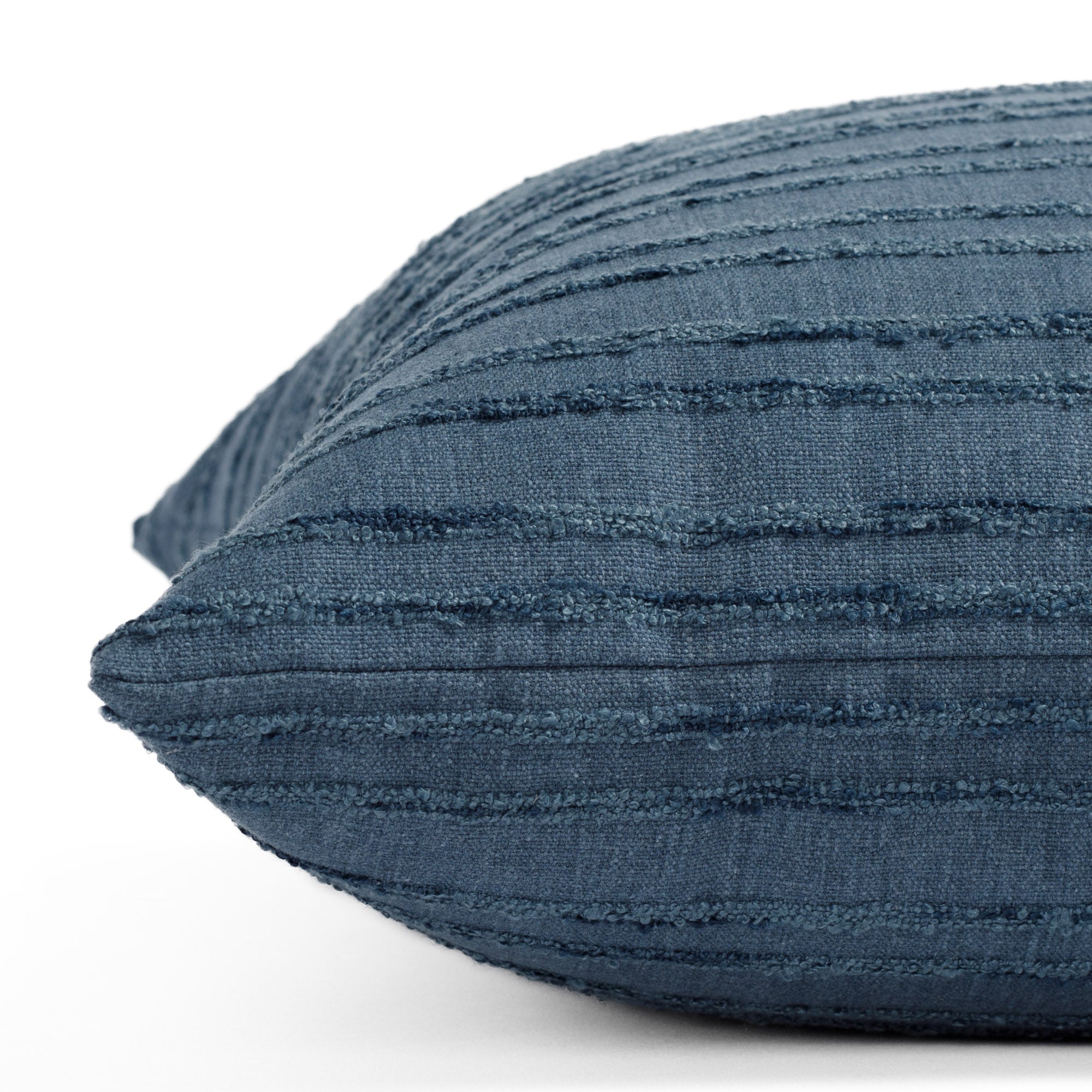 A denim blue tonal striped pillow: close up side view.