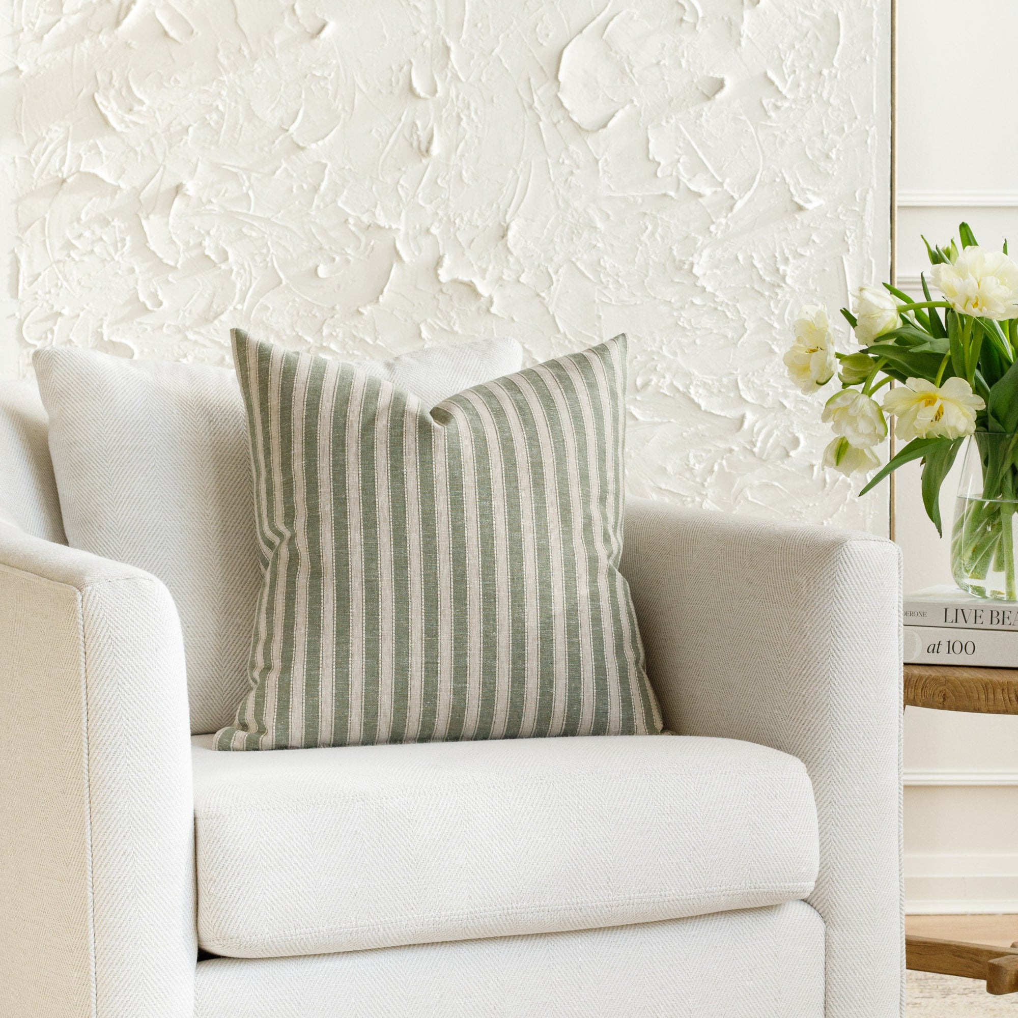 A green and beige pillow from Tonic Living, styled on a chair.