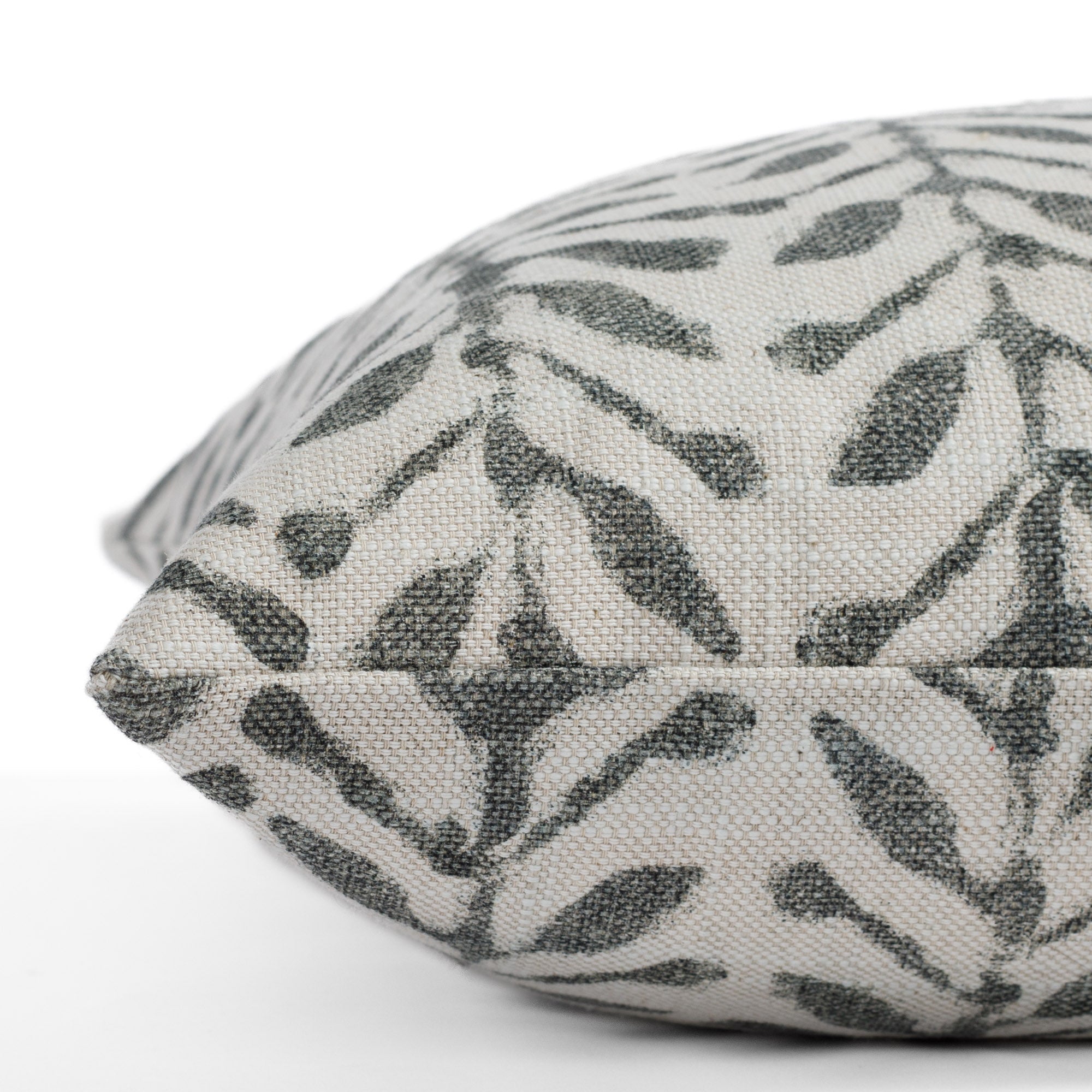 A charcoal and greige patterned pillow: a close up side view.